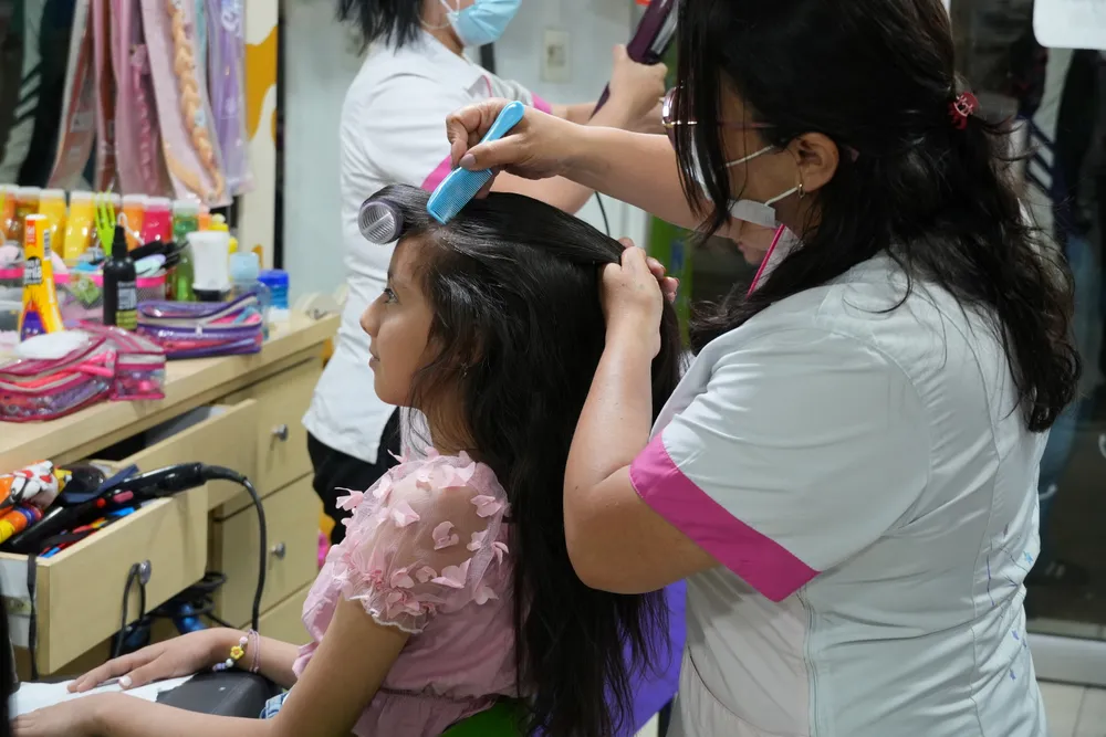 Estilista trenzando el cabello de una niña en Tinkerbell